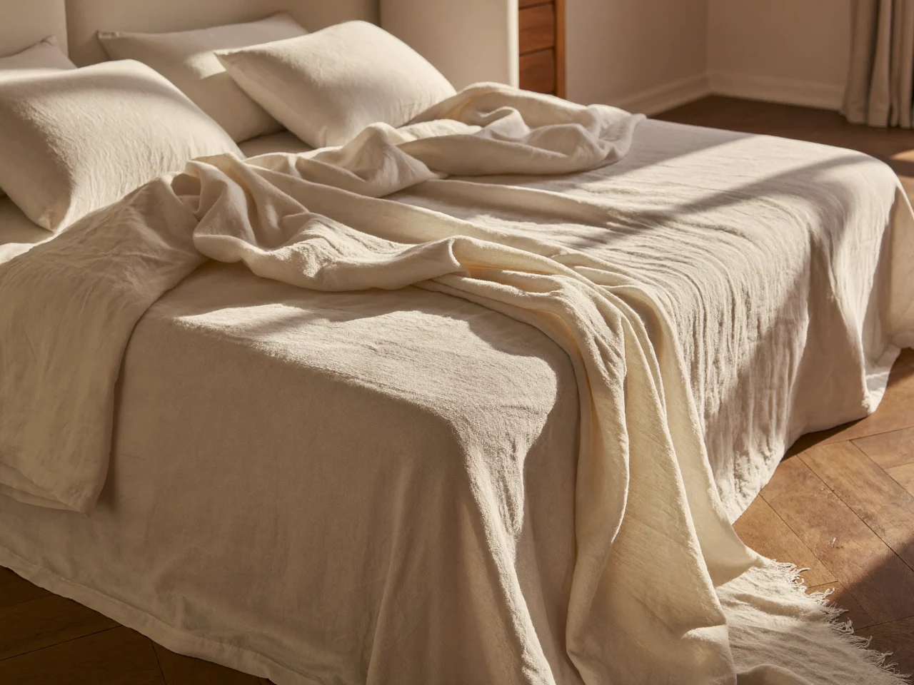 Sonniges Schlafzimmer mit zerknittertem Leinenbett und weichem Morgenlicht, illustrativ